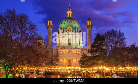 Festliche Stadtlandschaft - Blick auf den Weihnachtsmarkt am Karlsplatz und die Karlskirche in Wien, Österreich Stockfoto