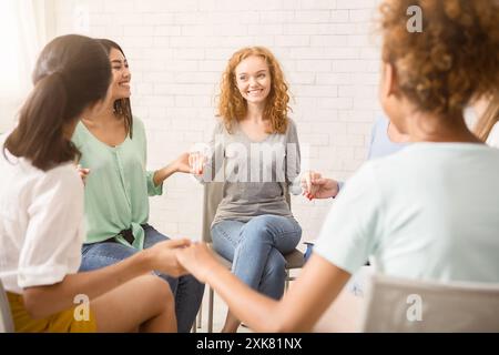 Diverse Mädchen lächelnd halten sich an den Händen sitzen innen Stockfoto