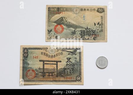 Alte japanische Währung zwei halbe Sen-Banknoten mit einer Yen-Münze. Half plus Half Sen Notes entsprechen 1 japanischen Yen Flat Lay in weißem Hintergrund Stockfoto