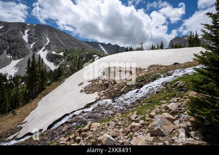 Schmelzender Gletscher auf dem Lake Isabelle Trail in Indian Peaks Wilderness, Colorado, unter sonnigen Sommerwolken. Stockfoto