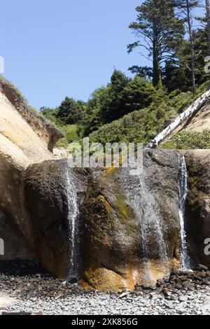 Ein kleiner Wasserfall am Hug Point in Arch Cape an der Küste Oregons an einem klaren Sommertag. Stockfoto