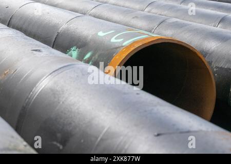 Reihen großer schwarzer Hohlbohrrohre. Die Enden sind rostig, die dünnwandigen Stahlrohre. Das schwere Industrierohr wird für Bohrungen im Bergbau verwendet Stockfoto