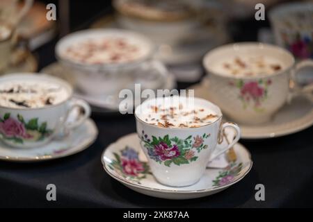 Ein Tisch mit mehreren traditionellen viktorianischen Teetassen aus Keramik mit verschiedenen Rosen- und Flora-Mustern auf den Porzellan-Getränketassen zum Verkauf. Stockfoto