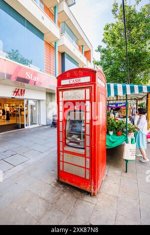 Eine traditionelle rote Telefonbox, die in einen Geldautomaten umgewandelt wurde, in einer Straße in Worcester, County Town of Worcestershire, West Midlands, England Stockfoto