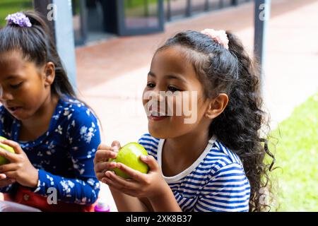 Zwei rassistische Mädchen, die in der Schule einen Snack im Freien genießen Stockfoto