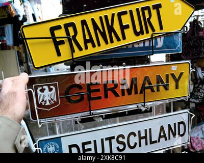 Frankfurt, Deutschland - 1. April 2024: In einem Souvenirladen in Frankfurt am Main greift eine männliche Hand nach einem Schild mit der Aufschrift Frankfurt, Deutschland, und hebt einen Hauch von lokalem Charme und Tourismus hervor Stockfoto