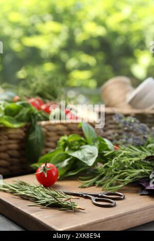 Verschiedene aromatische Kräuter, Gemüse und Scheren auf dem Tisch, Nahaufnahme Stockfoto