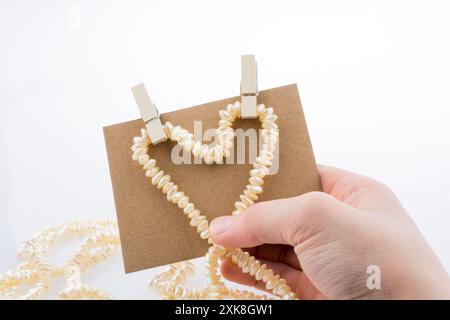 Perlenkette Formen Herz Form auf Papier auf weißem Hintergrund Stockfoto