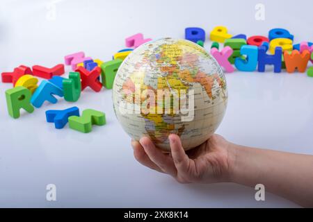 Kleines Modell gobe in Hand mit bunten Buchstaben hinter Stockfoto