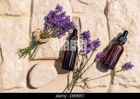 Zwei Kosmetiktropfflaschen mit einem natürlichen Gesichts- und Körperpflegeprodukt auf Basis von Lavendelöl. Bio-Kosmetik. Spa. Beigefarbener Hintergrund Stockfoto
