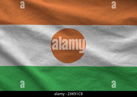 Niger-Flagge auf gefaltetem, gewelltem Stoff aus altem Tuch in Nahaufnahme dargestellt Stockfoto