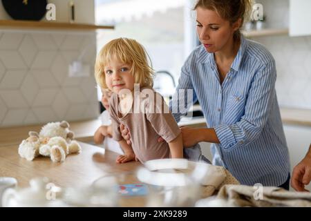 Mom und Kinder machen zusammen Pfannkuchen. Eltern und Kinder in der Küche, bereiten Pfannkuchenteig zu, verbringen den Wochenendtag drinnen. Stockfoto