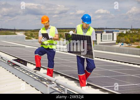 Elektroingenieure bei der einheitlichen Installation von Photovoltaik-Solarpaneelen auf dem Dach des Gebäudes Stockfoto