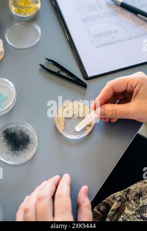 Wissenschaftlerinnen nehmen Proben von kleinen Kunststoffpartikeln aus Glitter auf Petrischale im Labor Stockfoto