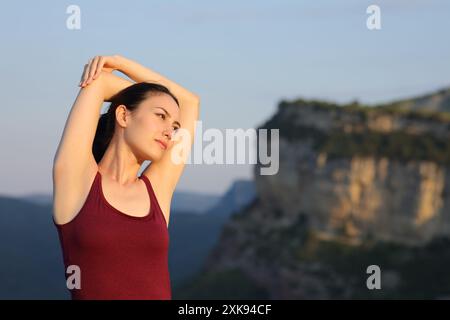 Ernsthafte asiatische Frau, die Arme in der Natur bei Sonnenuntergang streckt Stockfoto