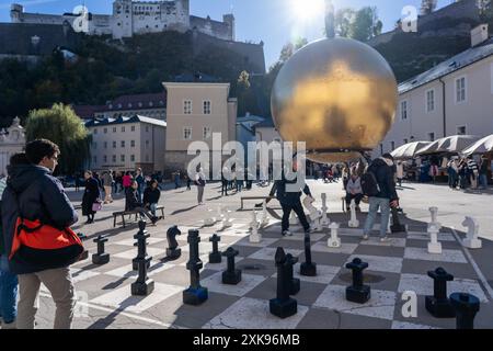 Salzburg, Österreich - 01. November 2023 : auf einem großen Schachbrett im Herzen von Salzburg, Österreich, befindet sich Eine riesige goldene Kugel. Stockfoto