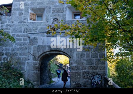 Salzburg, Österreich - 01. November 2023 : Ein Steinbogen in Salzburg, Österreich mit einem Paar und einem Kind, das durch die Stadt geht. Die Herbstlaub-Rahmen Stockfoto