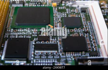 Detaillierte Nahaufnahme einer elektronischen Leiterplatte mit Mikrochips, Widerständen und anderen Komponenten, die moderne Technologie und Hardware repräsentieren. Stockfoto