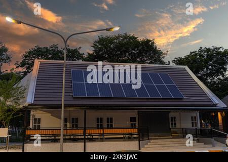 Fotocollage von Solarzellen, Photovoltaik auf dem roten Dach eines Hauses und einem schönen Himmel mit untergehenden Sonne. Alternative Stromversorgung. Konz Stockfoto