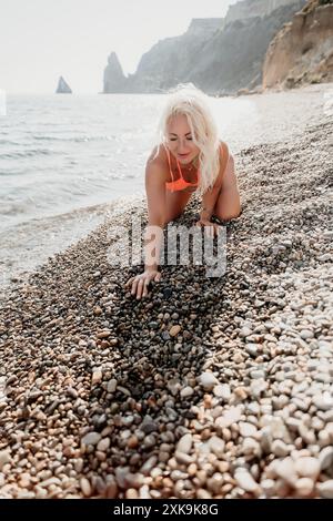 Frau in einem Bikini spielt an einem Kieselstrand Stockfoto