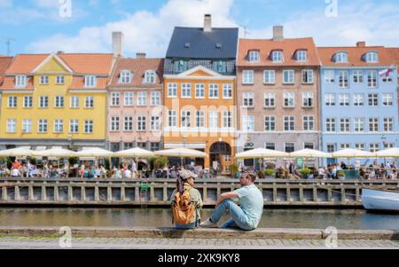 Ein Paar sitzt am Kanal in Kopenhagen und genießt den Blick auf farbenfrohe Gebäude und die geschäftige Atmosphäre der Stadt. Kopenhagen Dänemark Stockfoto