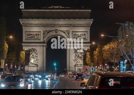 Paris, Frankreich - 19. Oktober 2023 : der Arc de Triomphe in Paris, Frankreich bei Nacht mit vorbeifahrenden Autos. Stockfoto