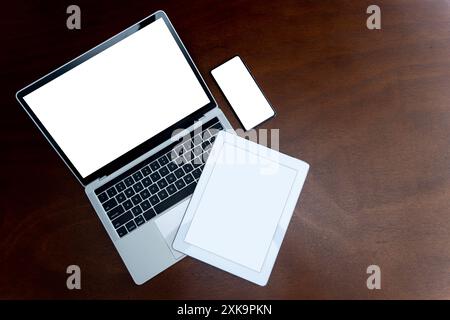 Laptops, Tablets und Smartphones mit leeren Bildschirmen auf dem Tisch, Geräte werden heutzutage in der Kommunikationstechnologie stark eingesetzt. Flache Draufsicht mit Kopie Stockfoto