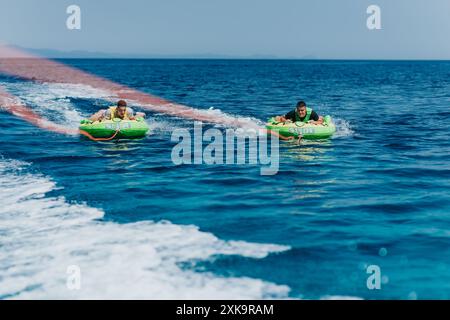 Männer genießen an einem sonnigen Sommertag im Meer das Tubing mit dem Schnellboot Stockfoto