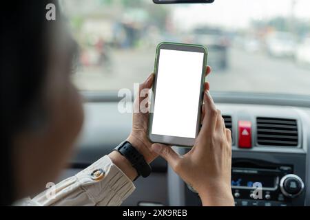 Glückliches Paar, das ein Smartphone mit leerem Bildschirm zeigt, während der Autofahrt mit ihrem Mann über das Mobiltelefon die Navigationskarte durchsucht Stockfoto