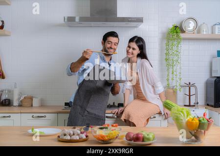 Mann, der für seine Freundin Frühstück macht. Ein junges verliebtes Paar, das Spaß hat, während es an einem schönen Morgen ein gemeinsames Frühstück zubereitete. Kochen, toget Stockfoto