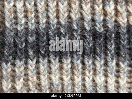 Gestrickte Wollstruktur, Nahaufnahme. Stricken. Strickhobbyarbeit. Streifenmuster aus Wollgarn. Warme Winterkleidung. Handarbeit-Konzept. Stockfoto