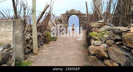 MADEIRA, PORTUGAL - 21. AUGUST 2021: Eine nicht identifizierte junge Frau steht im bogenförmigen Tor der Ruinen einer alten Zuckerfabrik. Stockfoto