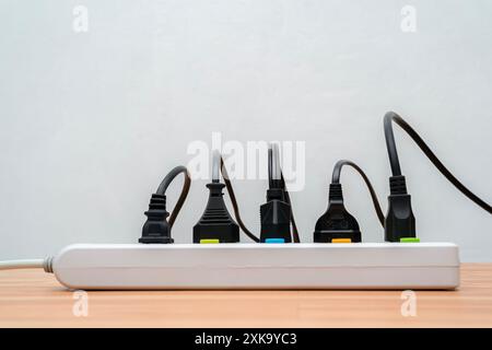 Viele Stecker sind mit einzelnen Schaltern an die Steckerleiste angeschlossen. Überspannungsschutz mit angeschlossenen weißen Drähten von elektrischen Geräten. Freier Speicherplatz. Soc Stockfoto