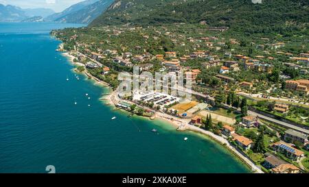 Malcesine, Gardasee, Italien - 20. Juli 2024: Aus der Vogelperspektive auf den Strand von Malcesine am Gardasee, Italien. Die malerische Küstenstadt beeindruckt mit ihren schönen Stränden, kristallklarem Wasser und der umliegenden Berglandschaft *** Luftaufnahme des Strandes von Malcesine am Gardasee, Italien. Der malerische Küstenort besticht durch seine schönen Strände, kristallklares Wasser und die umliegende Berglandschaft Stockfoto