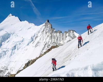 Drei Bergsteiger steigen vom Gipfel des Bischorns ab, einem Berg in den Schweizer Alpen. Stockfoto