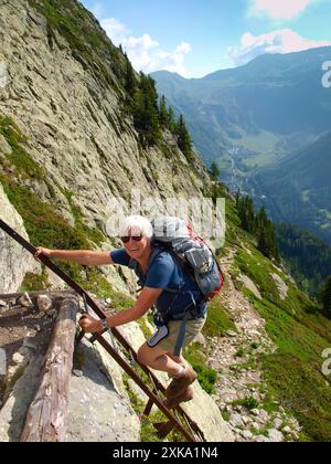 Eine ältere Dame klettert Leitern bei Lac Blanc in den Aiguilles Rouges zwischen Argentiere en Chamonix im Nationalpark Aiguilles Rouges. Stockfoto