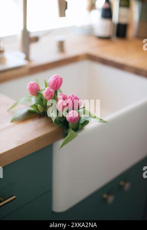 Pinkfarbene Tulpen auf Holztheke in einer gemütlichen Küche. Stockfoto