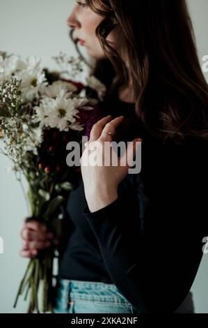 Eine Frau, die einen Blumenstrauß in der Nähe ihres Gesichts hält. Stockfoto