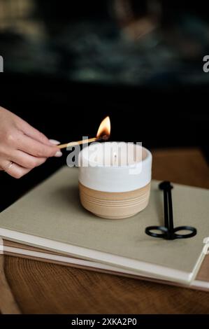 Eine Kerze auf gestapelten Büchern von Hand anzünden. Stockfoto