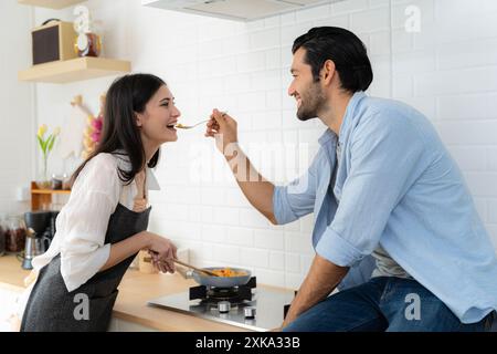 Ein junges verliebtes Paar, das Spaß hat, während es an einem schönen Morgen ein gemeinsames Frühstück zubereitete. Kochen, zusammen, Küche, Beziehung. Der Mann ist fe Stockfoto