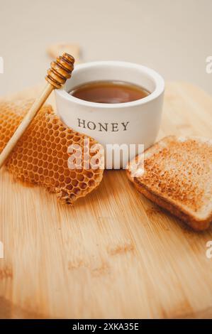 Gestylter Honiglöffel mit Toast auf Wurstplatte Stockfoto