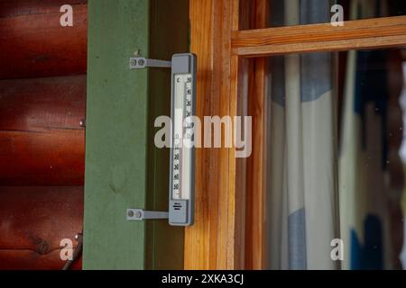 Außenthermometer außerhalb des Fensters des Holzhauses ist aus nächster Nähe. Thermometerskala mit plus Lufttemperatur. Eine Vorrichtung zur Bestimmung der Luft Stockfoto