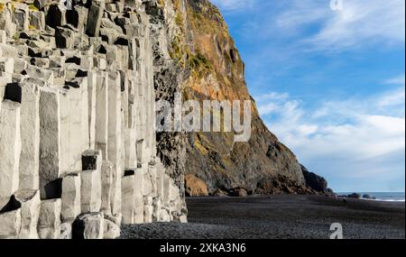 Gardar Basaltsäulen am Reynisfjara Black Sand Beach, Island. Eine felsige Klippe mit einer grau-weißen Felsformation. Die Klippe ist neben einem Strand und t Stockfoto