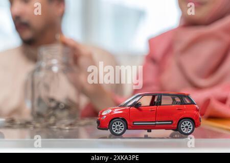 Muslimisches Paar mit einem Glas Münzen. Eine Frau, die Geld in das Glas steckt, das von einem Mann gehalten wird, spart Geld und investiert Geld für die Vorbereitung in der Zukunft. Stockfoto