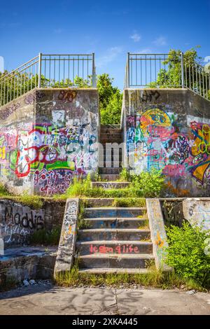 Mit Graffiti bedeckte alte Betongebäude, die von Unkraut überholt wurden Stockfoto