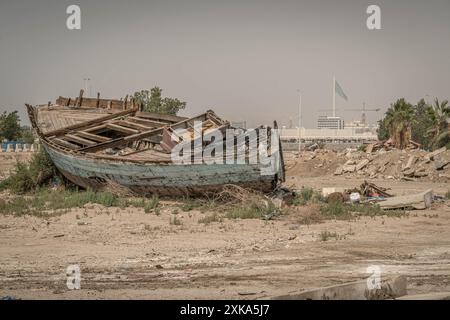 Das verlassene Holzboot in der saudischen Wüste mit der Flagge Saudi-Arabiens im Hintergrund. Stockfoto