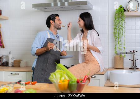 Ein junges verliebtes Paar, das Spaß hat, während es an einem schönen Morgen ein gemeinsames Frühstück zubereitete. Kochen, zusammen, Küche, Beziehung. Die Frauengebühr Stockfoto