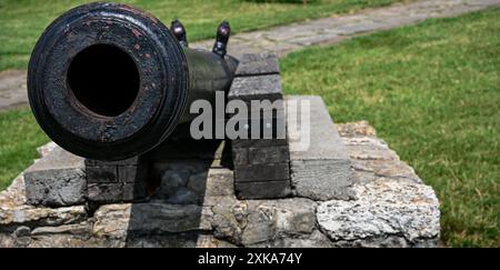 Alte, verwitterte Kanone, die auf feindliche Linien zeigt und eine Festung schützt. Stockfoto