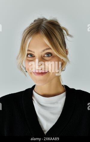 Eine junge, schöne Frau mit blonden Haaren in stilvoller Freizeitkleidung, die hell lächelt. Stockfoto