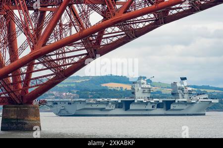 South Queensferry, Schottland, Großbritannien. Juli 2024. Die Royal Navy Flugzeugträger HMS Queen Elizabeth verlässt die Werft von Rosyth und segelt bei Ebbe unter der Forth Bridge nach Abschluss der Reparaturen. Iain Masterton/Alamy Live News Stockfoto